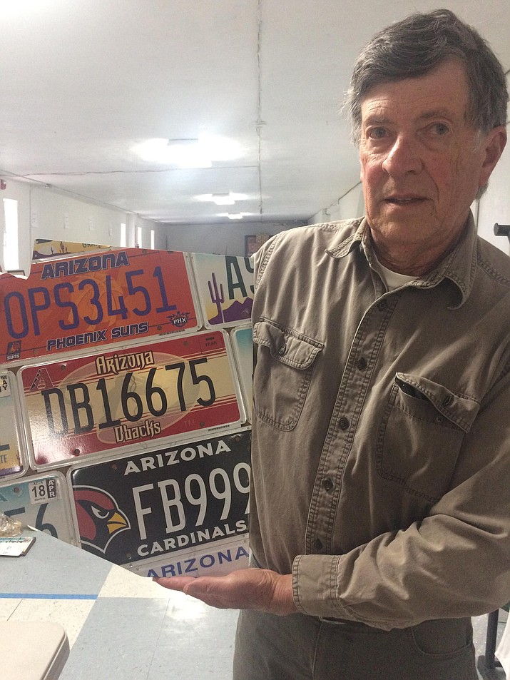 Jim Tilley holds a piece of license plate art up for auction during the 71st annual Kiwanis Auction. (Jason Wheeler/Courier)