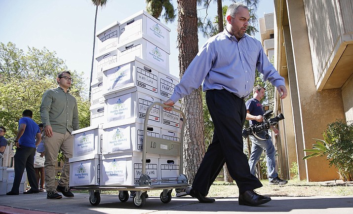 Arizona State Elections Director Eric Spencer, right, brings boxes to the elections office at the Arizona Capitol July 7, 2016, in Phoenix. Legislation to allow employers to pay some young people less than the voter-mandated minimum wage cleared a crucial hurdle Thursday, March 28, 2019, after its sponsor agreed it would not be tied to whether the worker was in school. (Ross D. Franklin/AP, file)