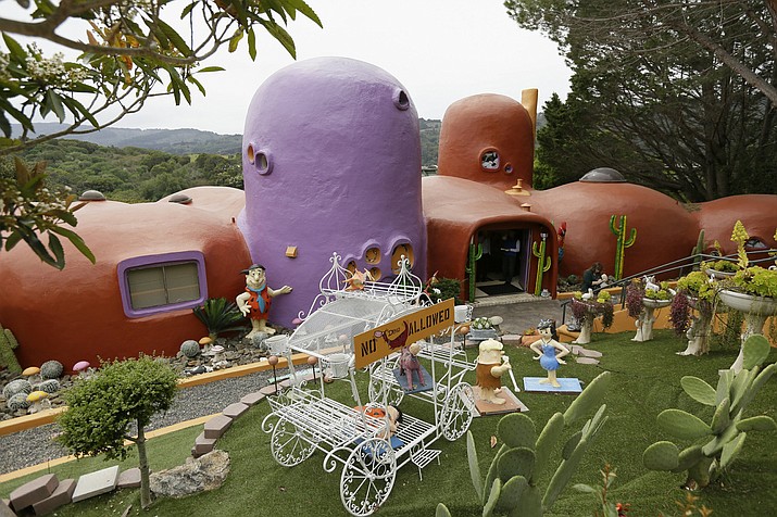 In this photo taken Monday, April 1, 2019, is an exterior view of the Flintstone House in Hillsborough, Calif. The San Francisco Bay Area suburb of Hillsborough is suing the owner of the house, saying that she installed dangerous steps, dinosaurs and other Flintstone-era figurines without necessary permits. (AP Photo/Eric Risberg)