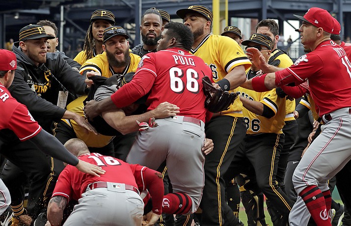 Cincinnati Reds' Yasiel Puig (66) is restrained by Pittsburgh Pirates bench coach Tom Prince, in the middle of a bench clearing brawl during the fourth inning of a baseball game in Pittsburgh, Sunday, April 7, 2019. (AP Photo/Gene J. Puskar)