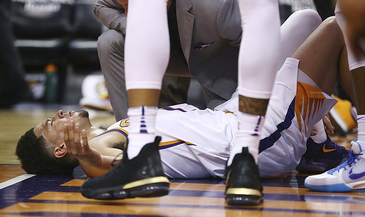 An injured Phoenix Suns guard Devin Booker pauses on the floor after turning his ankle during the first half of the team's NBA basketball against the Utah Jazz Wednesday, April 3, 2019, in Phoenix. Booker left the game. (Ross D. Franklin/AP)