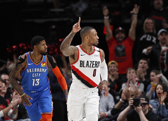 Portland Trail Blazers guard Damian Lillard, right, reacts after making a basket as Oklahoma City Thunder forward Paul George, left, trails the play during the first half of Game 1 of a first-round NBA basketball playoff series in Portland, Ore., Sunday, April 14, 2019. Steve Dipaola/AP)