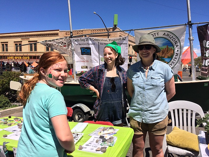 Hannah Hurley, 10, left, stops by the Earth Day table to speak with Prescott College students Camille Osburn and Taylor White in downtown Prescott Saturday, April 20. (Sue Tone/Courier)