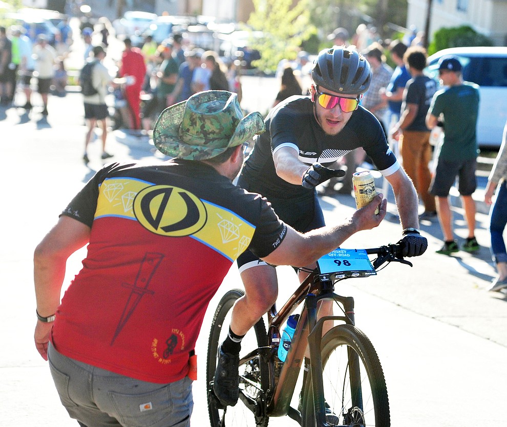 Levi Kurlander gets a beer handup during the Whiskey Off Road Fat Tire Crit through the streets of downtown Prescott Friday, April 26. (Les Stukenberg/Courier)