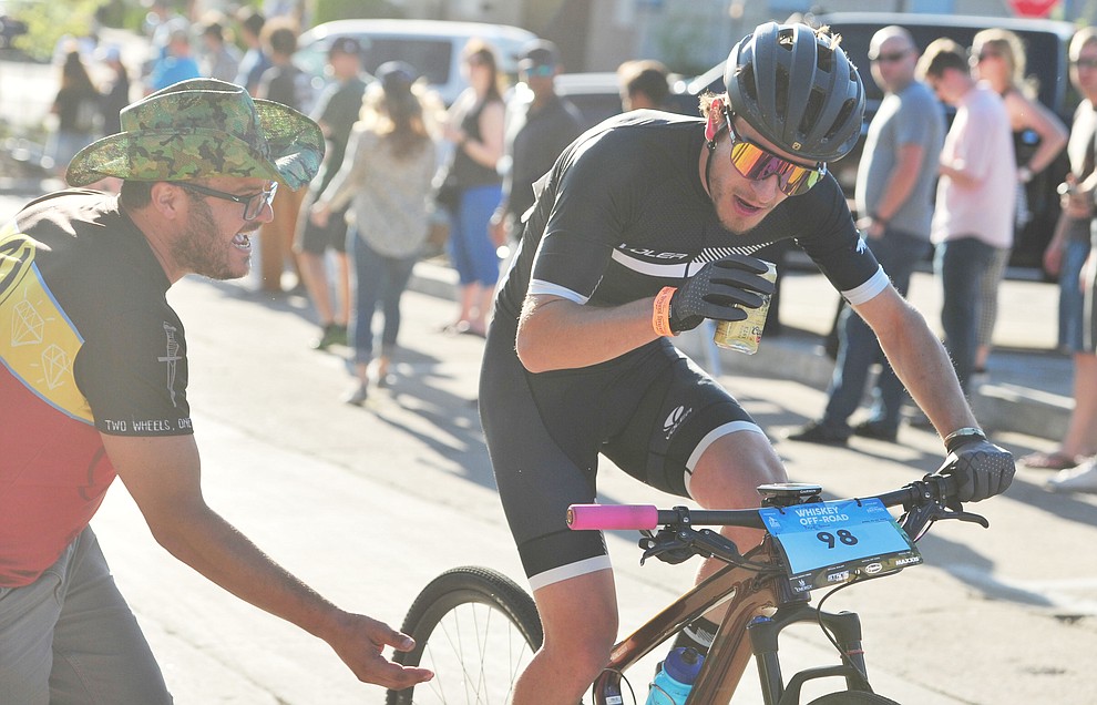 Levi Kurlander gets a beer handup during the Whiskey Off Road Fat Tire Crit through the streets of downtown Prescott Friday, April 26. (Les Stukenberg/Courier)