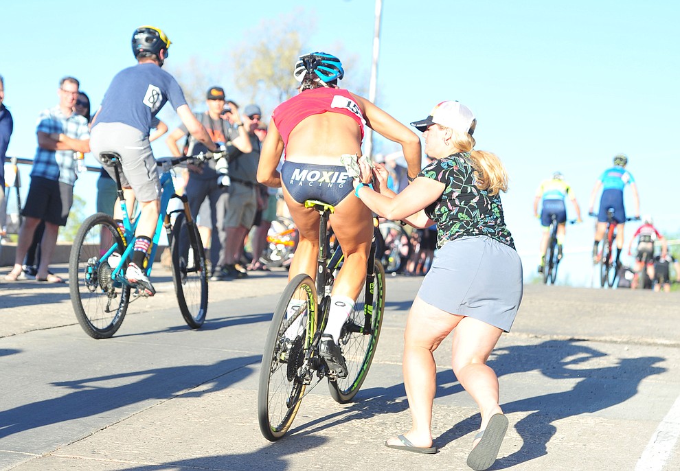 Evie Racette tucks a dollar into Evan Pardi's speedo during the Whiskey Off Road Fat Tire Crit through the streets of downtown Prescott Friday, April 26. (Les Stukenberg/Courier)