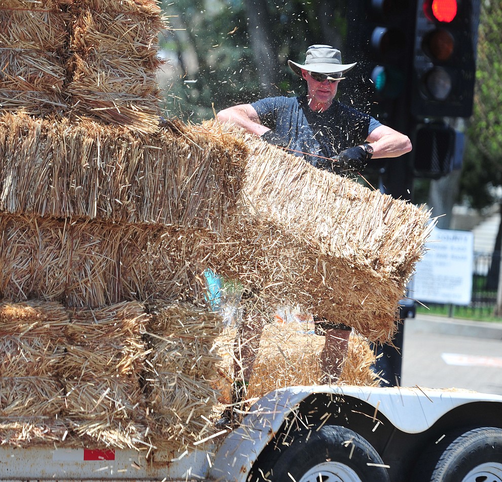 Ron Hart unloads hay bales for the Fat Tire Crit during the opening day of the Whiskey Off Road in downtown Prescott Friday, April 26. (Les Stukenberg/Courier)