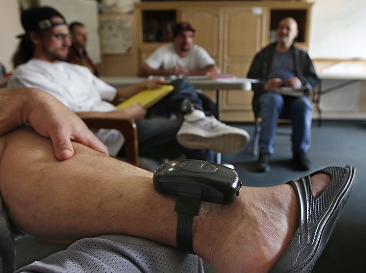 A GPS bracelet is seen on the ankle of an inmate attending a discussion Wednesday, Feb. 20, 2019, about living in sobriety at the Male Community Re-entry Program in Oroville, Calif. California's attempt to ease prison inmates transition back into the community is coming at a price, as an increasing number of prisoners simply walk away. Facilities like the one in Butte County, and in similar programs elsewhere are lightly guarded and inmates wear GPS bracelets that show their locations. (Rich Pedroncelli/AP)