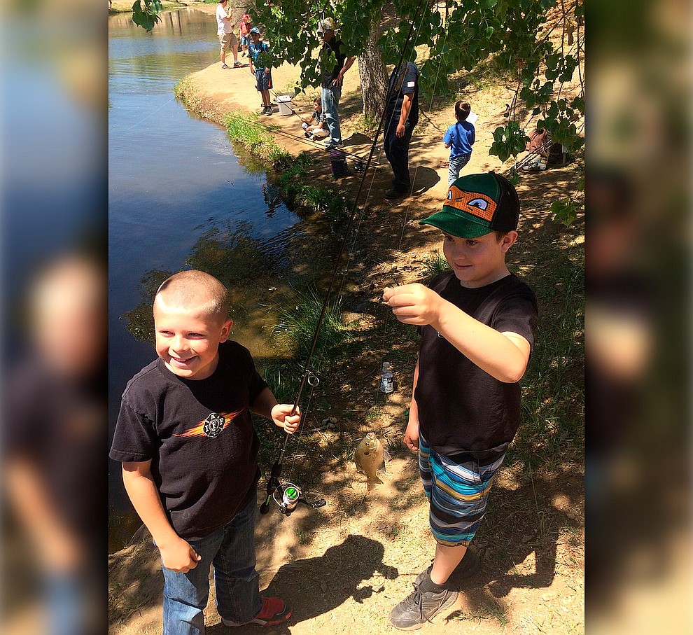 Rocco Smith and Lachlen Olson hold up a fish they caught during Badges & Bobbers at Fain Park Saturday, April 27. (Jason Wheeler/Courier)