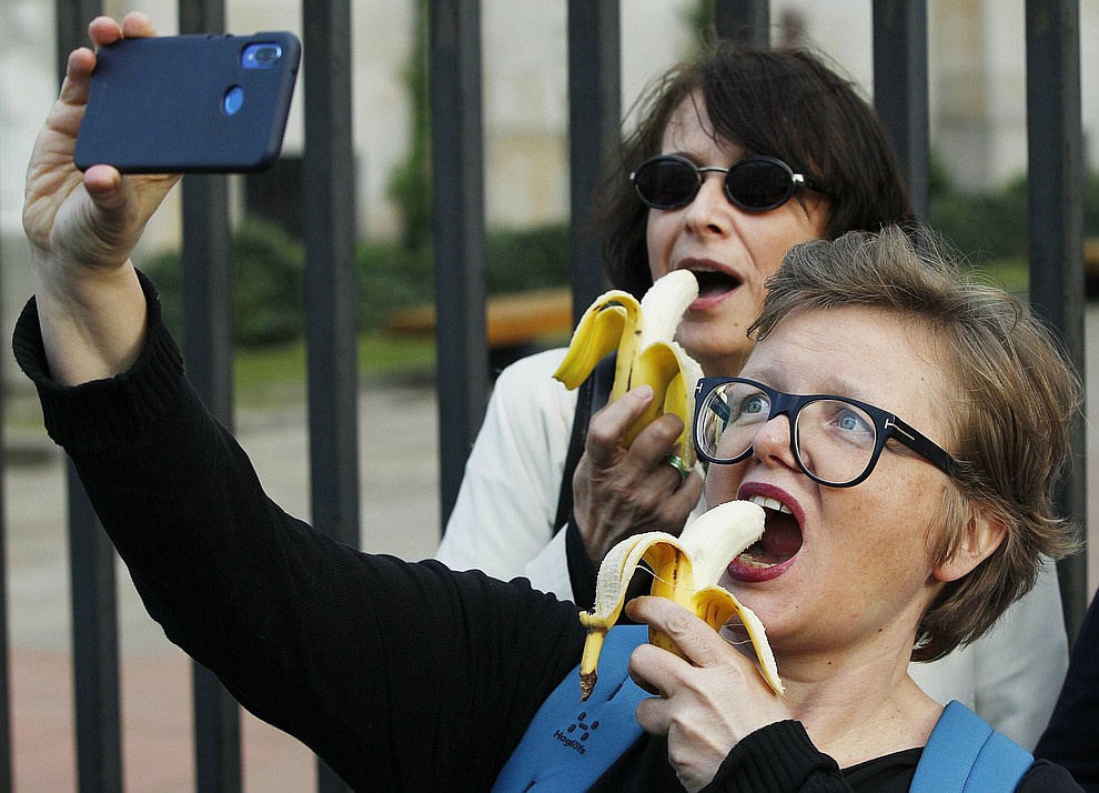 People with bananas demonstrate with others outside Warsaw's National Museum, Poland, Monday, April 29, 2019, to protest against what they call censorship, after authorities removed an artwork at the museum featuring the fruit, saying it was improper. (AP Photo/Czarek Sokolowski)