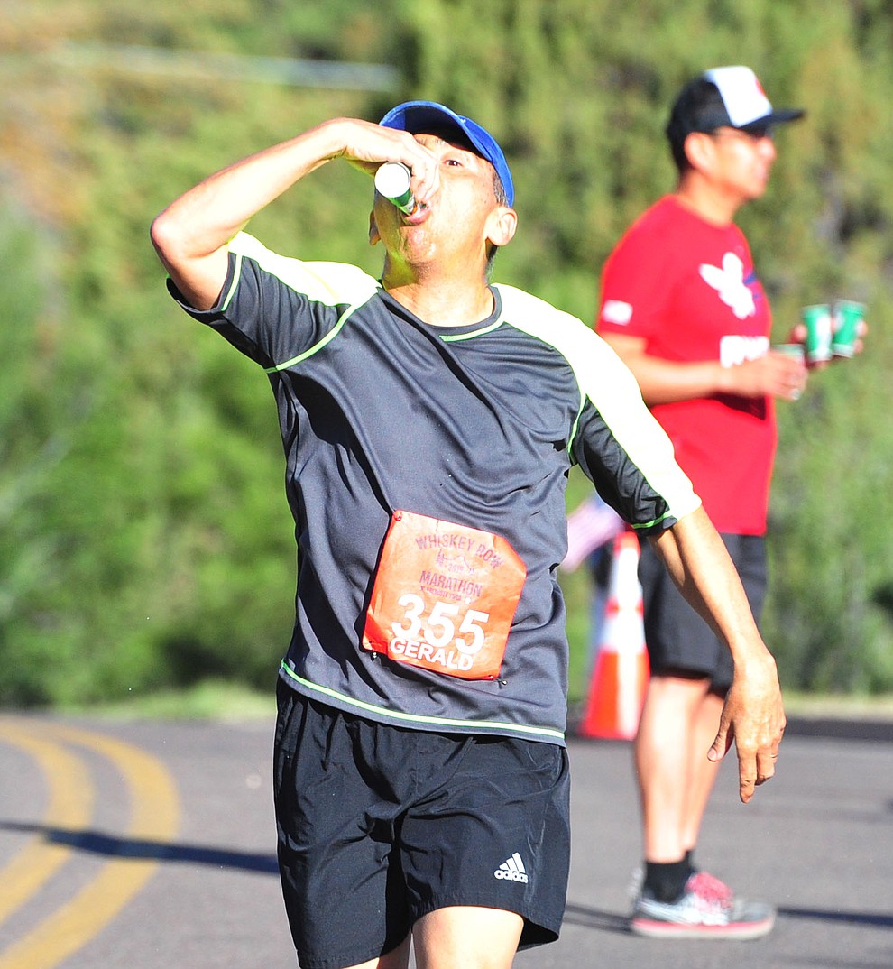 a half-marathon runner takes in water along Hassyampa during the 41st annual Whiskey Row Marathon Saturday, May 4. (Les Stukenberg/Courier)