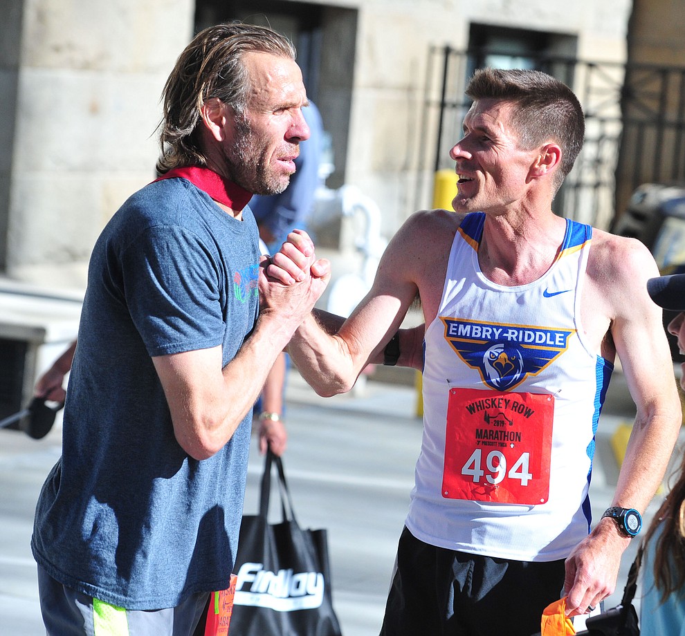 ERAU men's soccer coach Dan Balaguero gets congratulated by ERAU cross country coach Chris Bray on his win in the half-marathon during the 41st annual Whiskey Row Marathon Saturday, May 4. (Les Stukenberg/Courier)