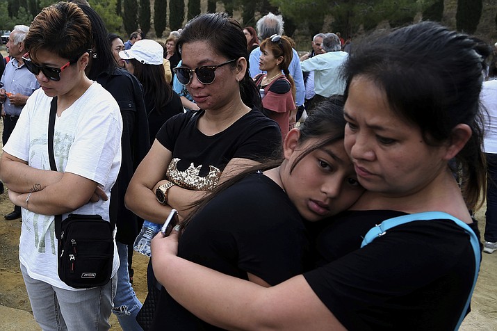 People attend a memorial for victims at the mineshaft where two female bodies were found near the village of Mitsero outside of the capital Nicosia, Cyprus, Sunday, May 5, 2019. Cyprus police spokesman Andreas Angelides says investigators hunting for bodies dumped by a suspected serial killer pulled a suitcase containing decomposing human remains from a toxic lake. (Petros Karadjias/AP)