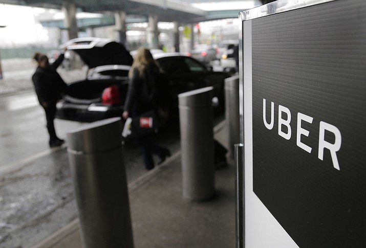 In this March 15, 2017, file photo, a sign marks a pick-up point for the Uber car service at LaGuardia Airport in New York. Drivers for ride-hailing giants Uber and Lyft are planning to turn off their apps to protest what they say are declining wages at a time when both companies are raking in billions of dollars from investors. (Seth Wenig/AP, File)