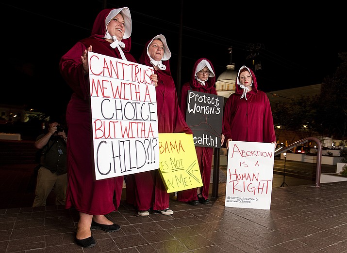 Anti-abortion ban bill protesters, dressed as handmaids, from left, Bianca Cameron-Schwiesow, Kari Crowe, Allie Curlette and Margeaux Hartline, wait outside of the Alabama statehouse after HB314, the near-total ban on abortion bill, passed the senate in Montgomery, Ala., on Tuesday, May 14, 2019. The measure now goes to Gov. Kay Ivey, who has not said whether she supports the measure. (Mickey Welsh/The Montgomery Advertiser via AP)