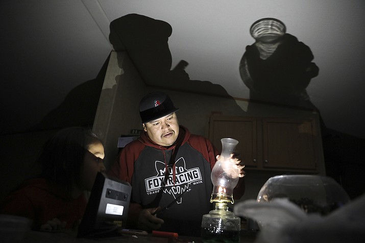 Jimmie Long Jr. places the glass on an oil lamp inside his Kaibeto home Wednesday, May 8, 2019, on the Navajo Reservation in Arizona. Long and his wife, Miranda Haskie, were spending one last night without electricity in their home before being connected to the grid on Thursday, May 16, 2019. (Jake Bacon/AP)