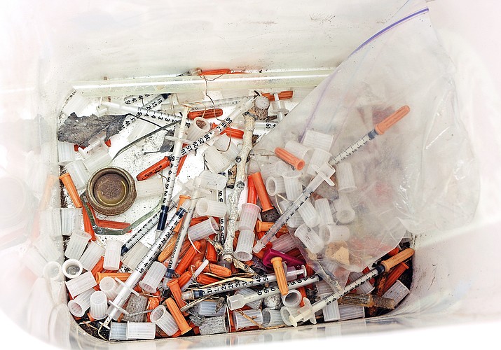 This May 8, 2019, photo shows hypodermic needles, needle caps, cotton swabs and other drug paraphernalia removed from Atrisco Park, home of the Atrisco Valley Little League, in Albuquerque, N.M. The little league park is fighting a battle against discarded syringes with attached hypodermic needles amid the region s outgoing opioid epidemic. (Jim Thompson/The Albuquerque Journal via AP)
