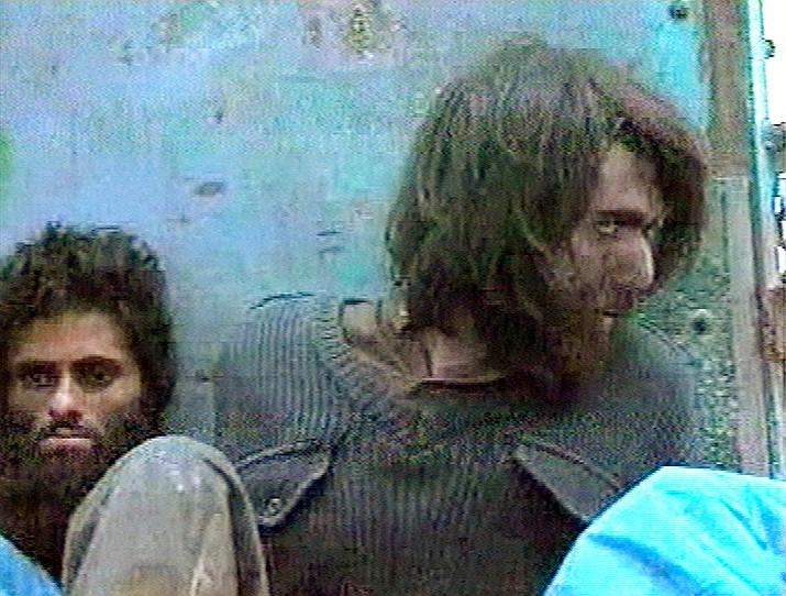 This file image taken Dec. 1, 2001, from television footage in Mazar-i-Sharif, Afghanistan, shows John Walker Lindh, right, claiming to be an American Taliban volunteer. Lindh, the young Californian who became known as the American Taliban after he was captured by U.S. forces in the invasion of Afghanistan in late 2001, is set to go free Thursday, May 23, 2019, after nearly two decades in prison. (AP Video, File)