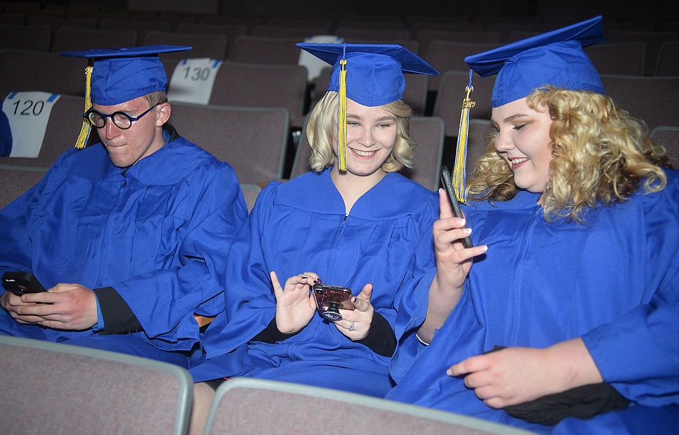 Alec Peterson, Stephanie Pasant and Cheyenne Williams check their phones before Prescott High School graduated 301 students in a commencement ceremony Friday, May 24 on Bill Shepard Field in Prescott. (Les Stukenberg/Courier)