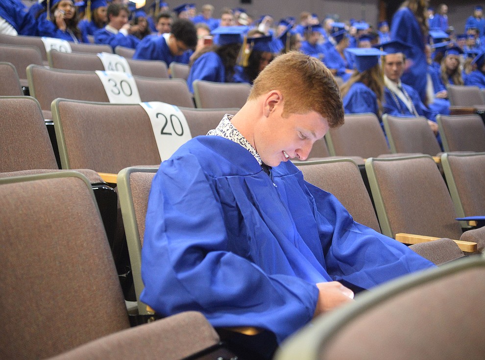 William Ramsay gets a laugh from his phone before Prescott High School graduated 301 students in a commencement ceremony Friday, May 24 on Bill Shepard Field in Prescott. (Les Stukenberg/Courier)