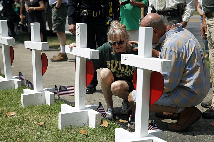A woman who did not wish to be identified kneels beside a cross for Michelle Langer, a victim of a mass shooting at a municipal building in Virginia Beach, Va., at a nearby makeshift memorial, Sunday, June 2, 2019. (Patrick Semansky/AP)