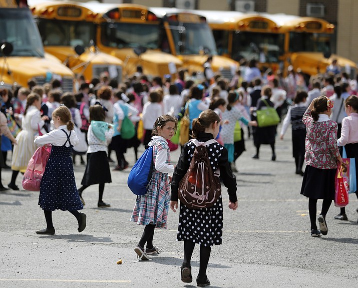 In this July 1, 2014 file photo, Orthodox Jewish girls walk to waiting buses after summer day camp in Kiryas Joel, N.Y. Kiryas Joel is a tightly packed Hasidic enclave surrounded by suburbia in the Hudson Valley. As a measles outbreak stretches toward summer camp season, New York counties with a concentration of Orthodox Jewish camps are requiring vaccinations for campers and staff. (Mike Groll/AP, file)
