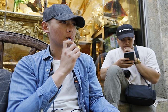 In this Monday, June 17, 2019, photo, Joshua Ni, 24, and Fritz Ramirez, 23, vape from electronic cigarettes in San Francisco. San Francisco supervisors are considering whether to move the city toward becoming the first in the United States to ban all sales of electronic cigarettes in an effort to crack down on youth vaping. The plan would ban the sale and distribution of e-cigarettes, as well as prohibit e-cigarette manufacturing on city property. (Samantha Maldonado/AP)