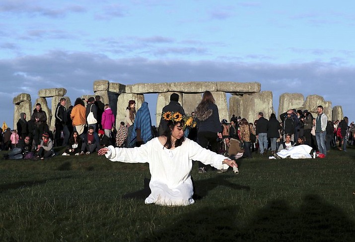 A reveler prays at sunrise as thousands gather at the ancient stone circle Stonehenge to celebrate the Summer Solstice, the longest day of the year, near Salisbury, England, Friday, June 21, 2019. (AP Photo/Aijaz Rahi)