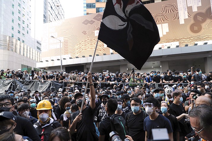 A protestor waves a black version of the Hong Kong flag outside the police headquarters in Hong Kong, Friday, June 21, 2019. More than 1,000 protesters blocked Hong Kong police headquarters into the evening Friday, while others took over major streets as the tumult over the city's future showed no signs of abating. (Kin Cheung/AP)