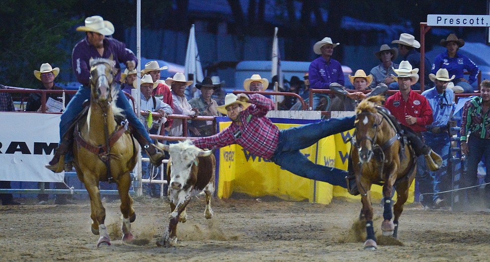 Denver Berry makes a long reach in the steer wrestling during the third performance of the Prescott Frontier Days Rodeo Wednesday July 3, 2019. (Les Stukenberg/Courier)