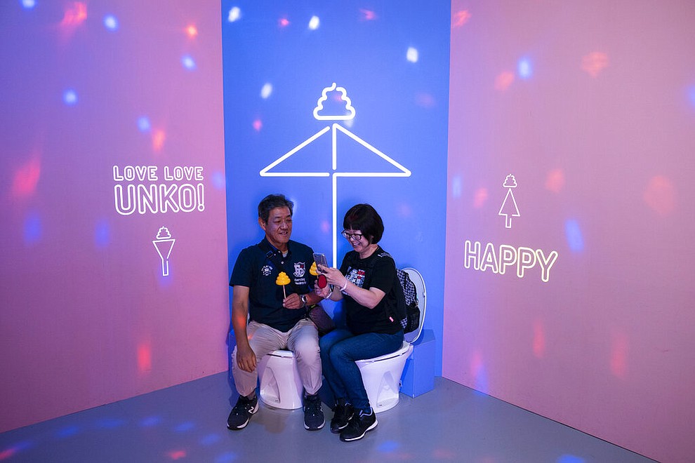 In this Tuesday, June 18, 2019, photo, a couple shares a light moment while sitting on toilet bowls at the Unko Museum in Yokohama, south of Tokyo. In a country known for its cult of cute, even poop is not an exception. A pop-up exhibition at the Unko Museum in the port city of Yokohama is all about unko, a Japanese word for poop. The poop installations there get their cutest makeovers. They come in the shape of soft cream, or cupcake toppings. (AP Photo/Jae C. Hong)