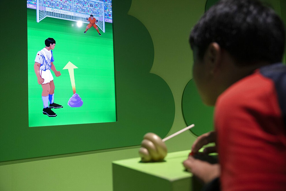 In this Monday, July 1, 2019, photo, a young boy plays a video game at the Unko Museum in Yokohama, south of Tokyo. In a country known for its cult of cute, even poop is not an exception. A pop-up exhibition at the Unko Museum in the port city of Yokohama is all about unko, a Japanese word for poop. The poop installations there get their cutest makeovers. They come in the shape of soft cream, or cupcake toppings. (AP Photo/Jae C. Hong)