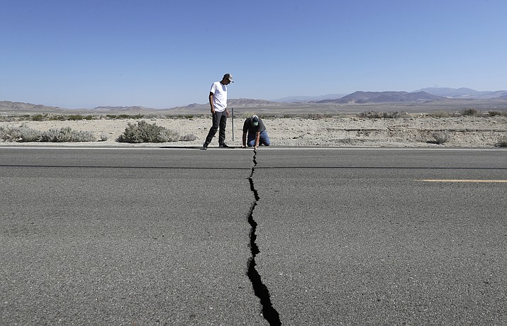 Ron Mikulaco, right, and his nephew, Brad Fernandez, examine a crack caused by an earthquake on Highway 178, Saturday, July 6, 2019, outside of Ridgecrest, Calif. (Marcio Jose Sanchez/AP)
