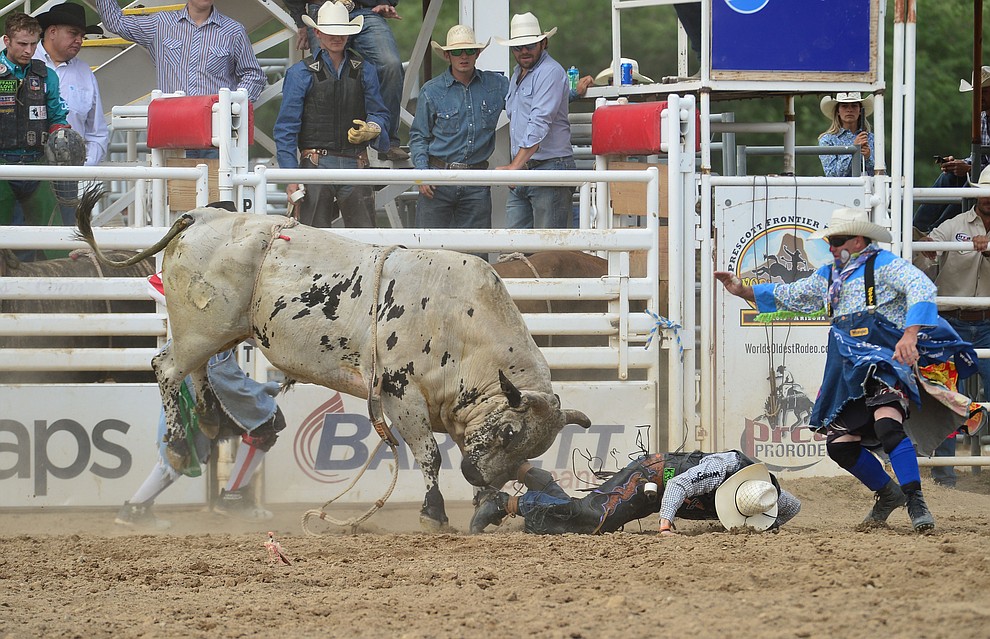 Bullfighter Luke Kraut moves in for the save after Brett Custer gets thrown from Last Cigarette in the bull riding during the final performance of the Prescott Frontier Days Rodeo Sunday July 7, 2019. (Les Stukenberg/Courier)