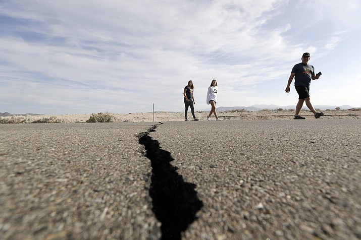 Visitors cross highway 178 next to a crack left on the road by an earthquake Sunday, July 7, 2019, near Ridgecrest, Calif. (Marcio Jose Sanchez/AP)