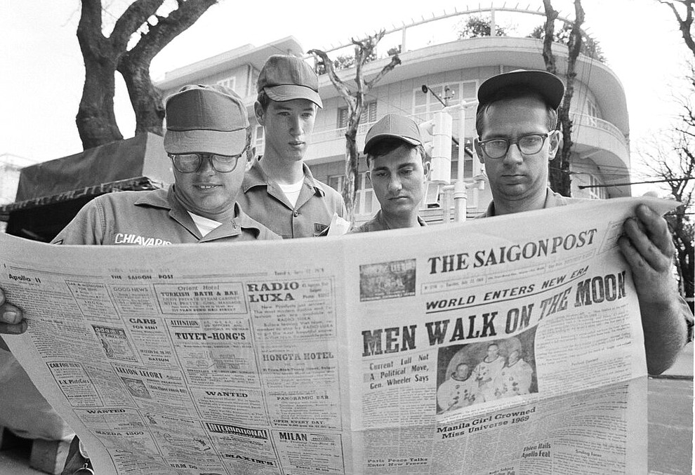 FILE - In this July 21, 1969 file photo, U.S. Air Force Sgt. Michael Chivaris, Clinton, Mass.; Army Spec. 4 Andrew Hutchins, Middlebury, Vt.; Air Force Sgt. John Whalin, Indianapolis, Ind.; and Army Spec. 4 Lloyd Newton, Roseburg, Ore., read a newspaper headlining the Apollo 11 moon landing, in downtown Saigon, Vietnam. (AP Photo/Hugh Van Es)