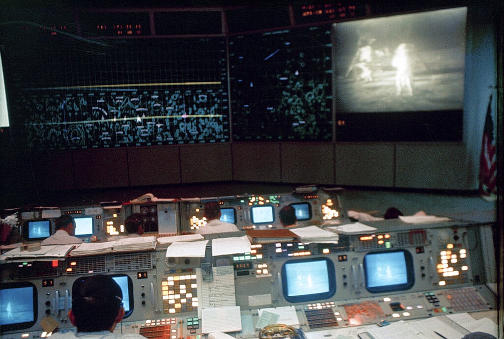 In this July 20, 1969 photo made available by NASA, flight controllers work in the Mission Operations Control Room in the Mission Control Center during the Apollo 11 lunar extravehicular activity. The television monitor shows astronauts Neil Armstrong and Buzz Aldrin on the surface of the moon. (NASA via AP)