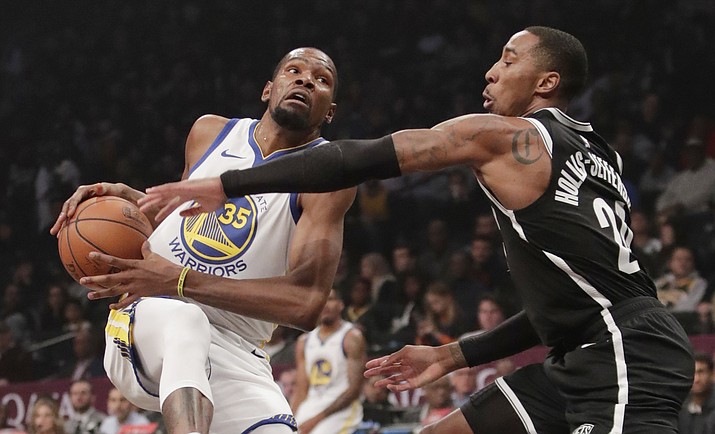 In this Oct. 28, 2018, file photo, Brooklyn Nets' Caris LeVert (22) defends against Golden State Warriors' Kevin Durant during the first half of an NBA basketball game in New York. Durant and Kyrie Irving gave the Nets two big victories in one night. In the first hours of free agency, the team added two of the best players available to a young roster that made the playoffs, giving them hope of not only contention for an NBA title, but to be the biggest basketball team in New York. (Frank Franklin II/AP, file)