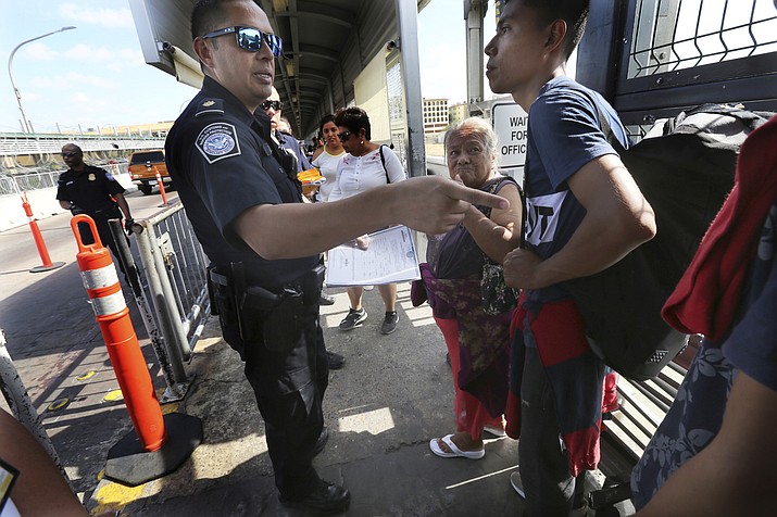 A United States Customs and Border Protection Officer checks the documents of migrants, before being taken to apply for asylum in the United States, on the International Bridge 1 in Nuevo Laredo, Mexico, Wednesday, July 17, 2019. Asylum-seekers grappled to understand what a new U.S. policy that all but eliminates refugee claims by Central Americans and many others meant for their bids to find a better life in America amid a chaos of rumors, confusion and fear. (AP Photo/Marco Ugarte)