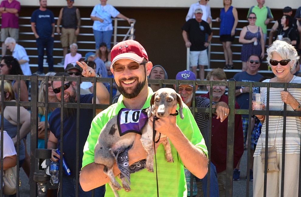 Devin Radell holds Loki the winner of the first heat of weiner dog racing at Arizona Downs in Prescott Valley Saturday July 20, 2019. (Les Stukenberg/Courier)