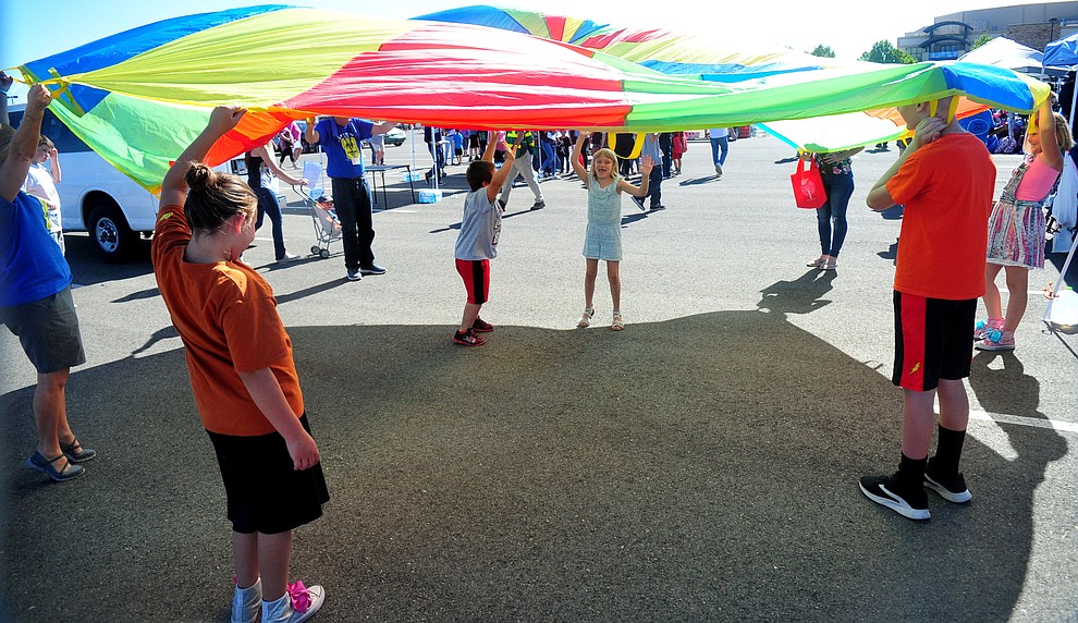 Kids play under a parachute as the Yavapai Food Bank gave away 1300 backpacks in the parking lot of Findlay Toyota Center Saturday July 27, 2019 in Prescott Valley. (Les Stukenberg/Courier)