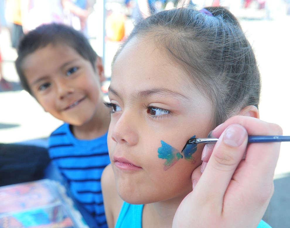 Frank S. watches as his sister Mia gets her face painted as the Yavapai Food Bank gave away 1300 backpacks in the parking lot of Findlay Toyota Center Saturday July 27, 2019 in Prescott Valley. (Les Stukenberg/Courier)