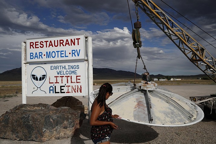 In this July 22, 2019 photo, Grace Capati looks at a UFO display outside of the Little A'Le'Inn, in Rachel, Nev., the closest town to Area 51. The U.S. Air Force has warned people against participating in an internet joke suggesting a large crowd of people "storm Area 51," the top-secret Cold War test site in the Nevada desert. (AP Photo/John Locher)
