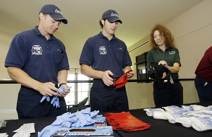 Emergency responders Justin Ernst, left, Steve Mayhew, center, and Sue Pistoia, of the Community Emergency Response Team CERT, assemble personal protection equipment kits for upcoming emergency flu training April 30, 2009, in Avondale. The Emergency Management Division of the Arizona Department of Emergency and Military Affairs offers certification in Community Emergency Response Team Basic Training over three days, Sept. 25-27. (Ross D. Franklin/AP, file)