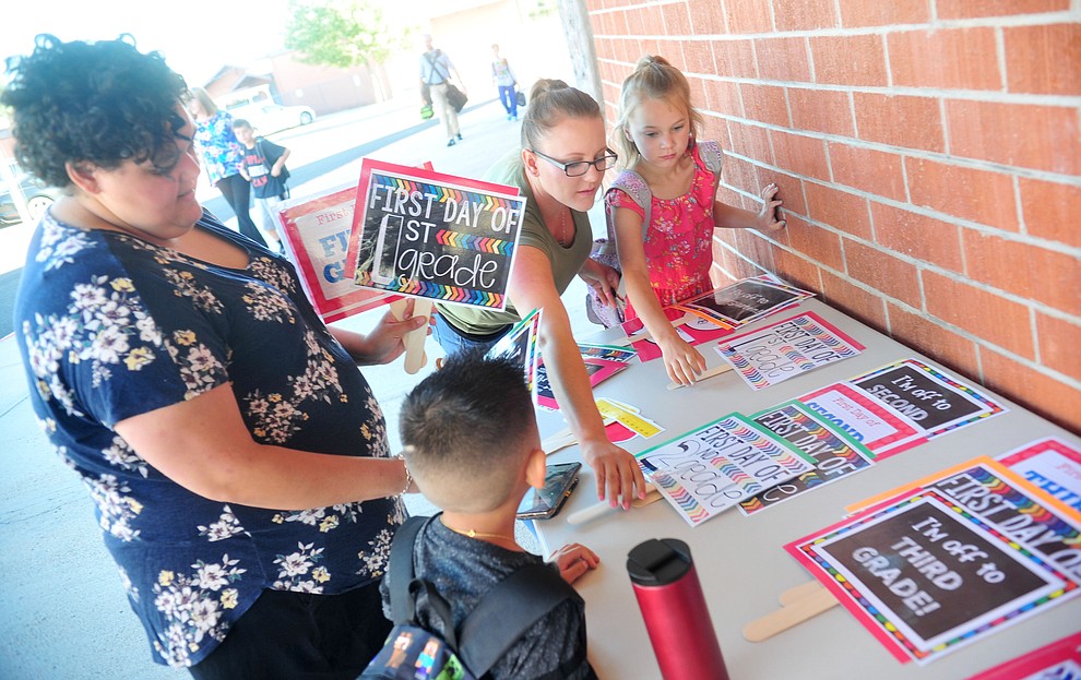 First grader Zander Grijalva with his mother Alessandra along with Amber Ryan and second grader Rylee Ryan look for the perfect sign for their picture for the first day of school at Taylor Hicks Elementary School in Prescott Thursday, August 1, 2019. (Les Stukenberg/Courier)