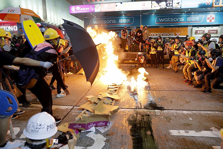 Protesters burn cardboard to form a barrier as they confront with police in Hong Kong on Saturday, Aug. 3, 2019. Hong Kong protesters removed a Chinese national flag from its pole and flung it into the city's iconic Victoria Harbour on Saturday, and police later fired tear gas at demonstrators after some of them vandalized a police station. (AP Photo/Kin Cheung)
