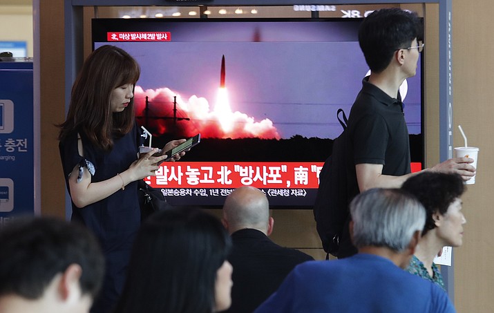 People watch a TV showing a file image of North Korea's missile launch during a news program at the Seoul Railway Station in Seoul, South Korea, Tuesday, Aug. 6, 2019. North Korea on Tuesday continued to ramp up its weapons demonstrations by firing unidentified projectiles twice into the sea while lashing out at the United States and South Korea for continuing their joint military exercises that the North says could derail fragile nuclear diplomacy. The sign reads "North Korea's multiple rocket launchers system." (AP Photo/Ahn Young-joon)