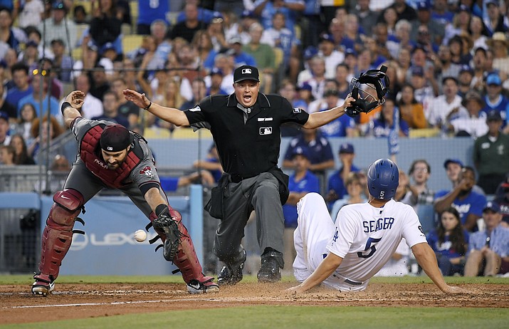 Los Angeles Dodgers’ Corey Seager, right, scores on a sacrifice bunt by Kenta Maeda, of Japan, as Arizona Diamondbacks catcher Alex Avila, left, takes the throw and home plate umpire Cory Blaser, center, makes the call during the fourth inning of a game Saturday, Aug. 10, 2019, in Los Angeles. (Mark J. Terrill/AP)