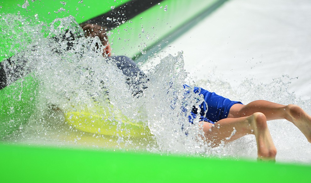 Nate Vandervort hits the bottom of the slide at the annual Monsoon Festival with the water slide that stetches most of the length of Union Street Saturday, August 17, 2019, in downtown Prescott. (Les Stukenberg/Courier)