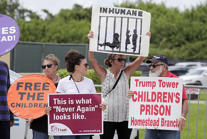 In this July 15, 2019, file photo, protesters hold signs outside of the Homestead Temporary Shelter for Unaccompanied Children while members of Congress tour the facility in Homestead, Fla. The government will be able to hold immigrant children detained at the Mexican border for a longer period of time under a move by the Trump administration. (AP Photo/Lynne Sladky, File)